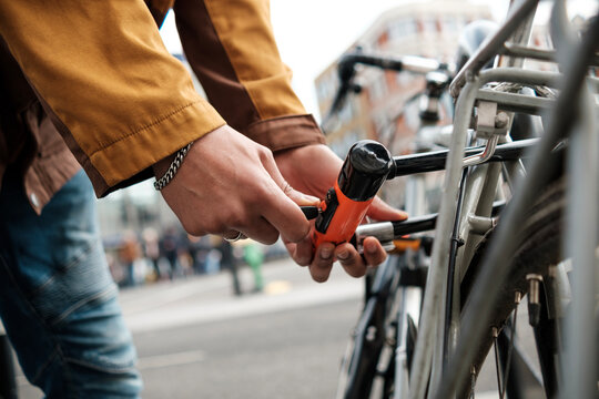 Cyclist securing bike with u-lock on city street - Powered by Adobe