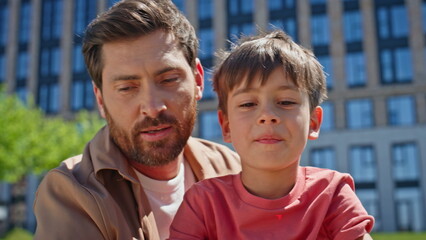 Closeup father son talking at nature. Man speaking to child enjoying picnic