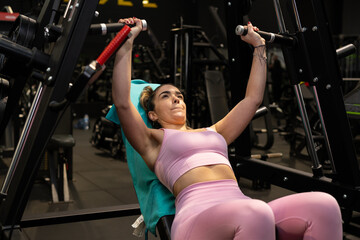 Determined sportswoman lifting weights on bench press machine in gym