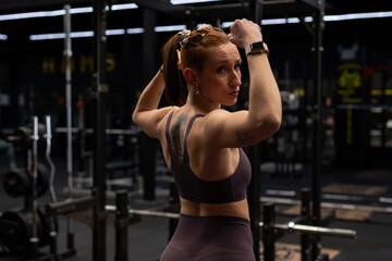 Determined sportswoman tying hair in gym after workout