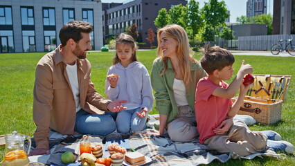 Parents kids enjoy picnic on green grass near apartment. Family children eating