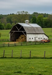 Obraz premium White Barn with Hay Bales and a Vintage Truck in a Green Field