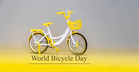 Selbstklebende Fototapeten Fahrrad World bicycle day text Toy bicycle white, violet, grey background.     © MARINA