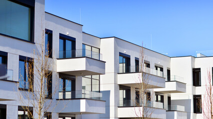 Obraz premium Modern architecture of urban residential apartment buildings on a sunny day. Low-rise apartment buildings with large windows and extensive terraces. White facade of a modern apartment building.