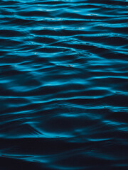 Dark blue water surface with ripples and reflections.  The image is moody and atmospheric.