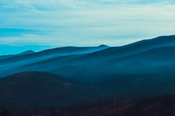 Mountain Serenity: A panoramic view of majestic mountain ranges fading into the distance, veiled in...