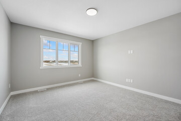 Large, empty room with a window and a light fixture