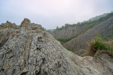 Wide view of the eroded white mudstone badlands of Caoshan Moon World in Tainan, Taiwan. The stark,...