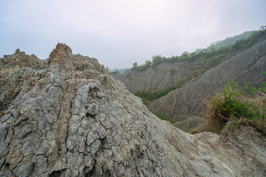Wide view of the eroded white mudstone badlands of Caoshan Moon World in Tainan, Taiwan. The stark, barren landscape features sharp ridges and deep gullies with sparse vegetation.