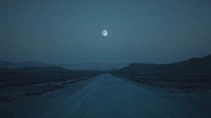 Fototapeta premium Serene Moonlit Road in Desert Landscape at Dusk with Clear Night Sky and Mountains in the Background