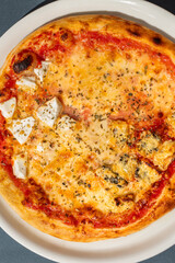 Four cheese pizza, homemade Italian pizza. Pizza on dark gray background. Traditional Italian cuisine. Place for text, top view.