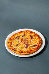 Pizza with mozzarella cheese, ham and sauce on plain grey background