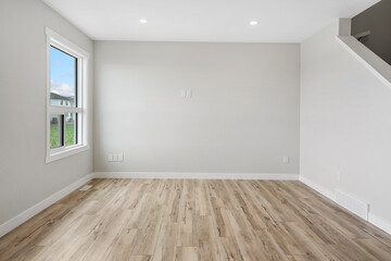 Large, empty room with a window and a staircase