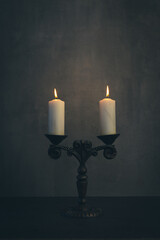 Beautiful vintage brass candelabrum with two burning candles in the dark, vertical image.