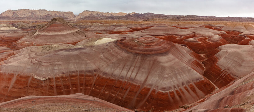 This landscape panorama features the colorful Bentonite Hills of the southern San Rafael Swell in Utah.  Rising behind, the tilted fins of the San Rafael Reef.