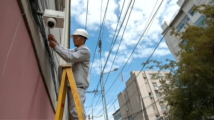 Worker installing a surveillance camera in a breezy alley