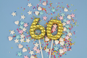 Gold birthday candles and many colorful sprinkles on blue background. Number 60.