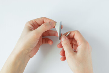Self-adhesive metal chrome hook on the wall in the hands of a Caucasian woman. Tears off the sticky...