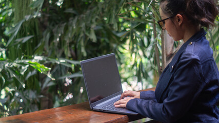 Businesswoman working on laptop on rich tree background in cafe, freelancer girl with independent working time with comfortable working anywhere