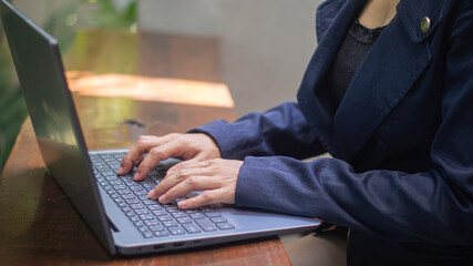 Close-up of businesswoman's hand typing something on laptop in bright atmosphere and empty space for text.