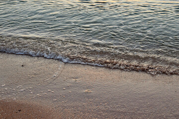 Sea waves crash onto the sandy shore on a summer morning