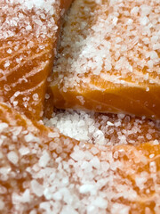 A vertical close-up shot of fresh trout steaks generously seasoned with coarse sea salt, highlighting the texture of both the fish and the salt crystals during the preparation process.
