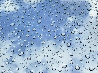 Rain drops at mirror with cloudy blue sky