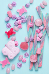Multicolored assorted sweets, lollipops and candies on a blue background. Top view. Colorful assortment of candy and sprinkles on a blue background