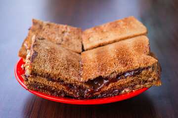 A plate of traditional Singaporean Chocolate Toast with melted filling and crispy bread texture on a wooden table with bokeh background