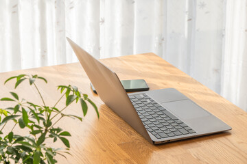 テーブルの上に置かれたノートパソコンとスマホ