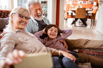Happy grandparents taking a selfie with their grandson at home