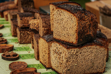 Close-up of stacked slices of dark rye bread with a rich, rustic crust and soft, airy texture. Some...