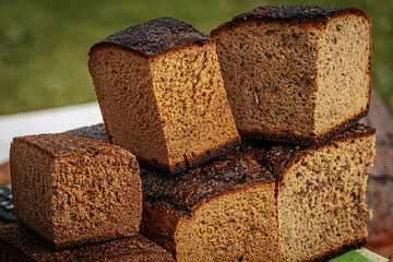 Close-up of stacked slices of dark rye bread with a rich, rustic crust and soft, airy texture. Some pieces include seeds, showcasing artisanal baking quality.
