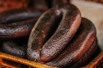 Close-up of blood sausages with grains in a coiled arrangement inside a woven basket, showcasing...