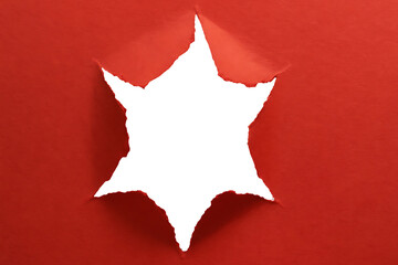 Red Paper Starburst: A burst of white light shines through a star-shaped hole torn in a sheet of vibrant red paper, creating a dynamic and eye-catching design.