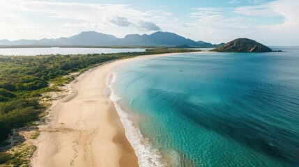 Obraz premium Aerial view of a tropical beach with clear turquoise water and mountains in the background on a sunny day