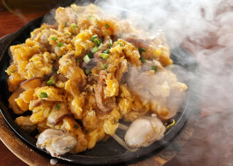 Close-up the Oyster omelette hot pan on wooden table.