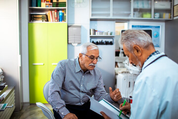 Senior man consulting with doctor while reviewing X-ray scan in medical office