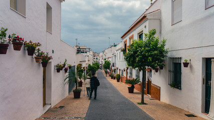 Enjoying early morning tranquility amongst an abundance of flowers and blossoms in a narrow street in Old Town Estepona, Spain.