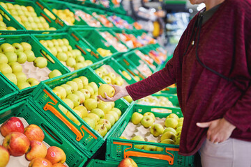 Woman selecting green apple at fruit section in supermarket