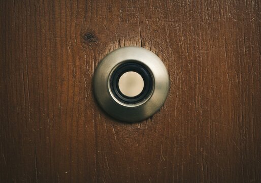 Sonnette ronde metallique sur bois fonc&eacute; ambiance chaleureuse. AI Generated