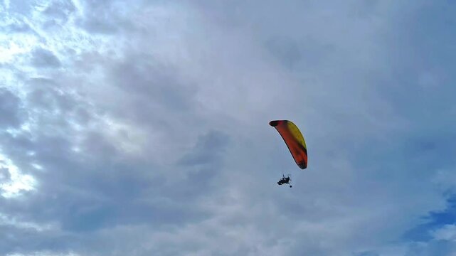 View of paramotor passed with beautiful sky cloud and waves on the beach. Indonesian paramotor in Pangandaran beach. Extreme sport in the nature