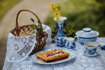 Easter still life on the table with mazurek cake, basket, flowers and porcelain