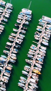 Aerial top view of rows of yachts and sailboats at the marina against the turquoise water of the lagoon. Hawaii, Oahu Island. Vertical video.