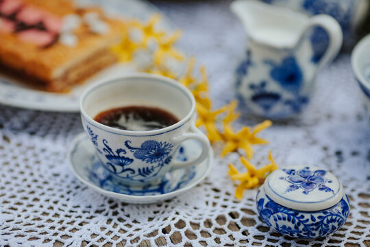 Cup of black coffee and cake on the table with yellow flowers - spring breakfast