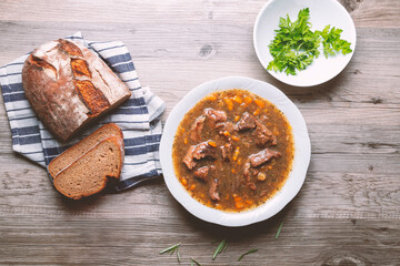 Meat goulash with vegetables on a wooden background.