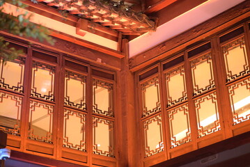 the corner of a room with wooden walls and ornate window frames. The panels have a decorative...