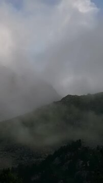 Misty Mountain Landscape at Sunrise With Rolling Fog Over the Hills. A tranquil view of mountains shrouded in mist as the sun begins to rise.
