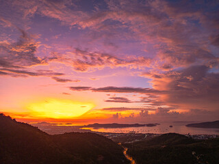 A breathtaking sunset paints the sky in vivid hues of orange and blue over a coastal town, with...