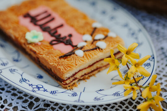 Easter mazurek cake with chocolate and caramel on a plate with yellow spring flowers